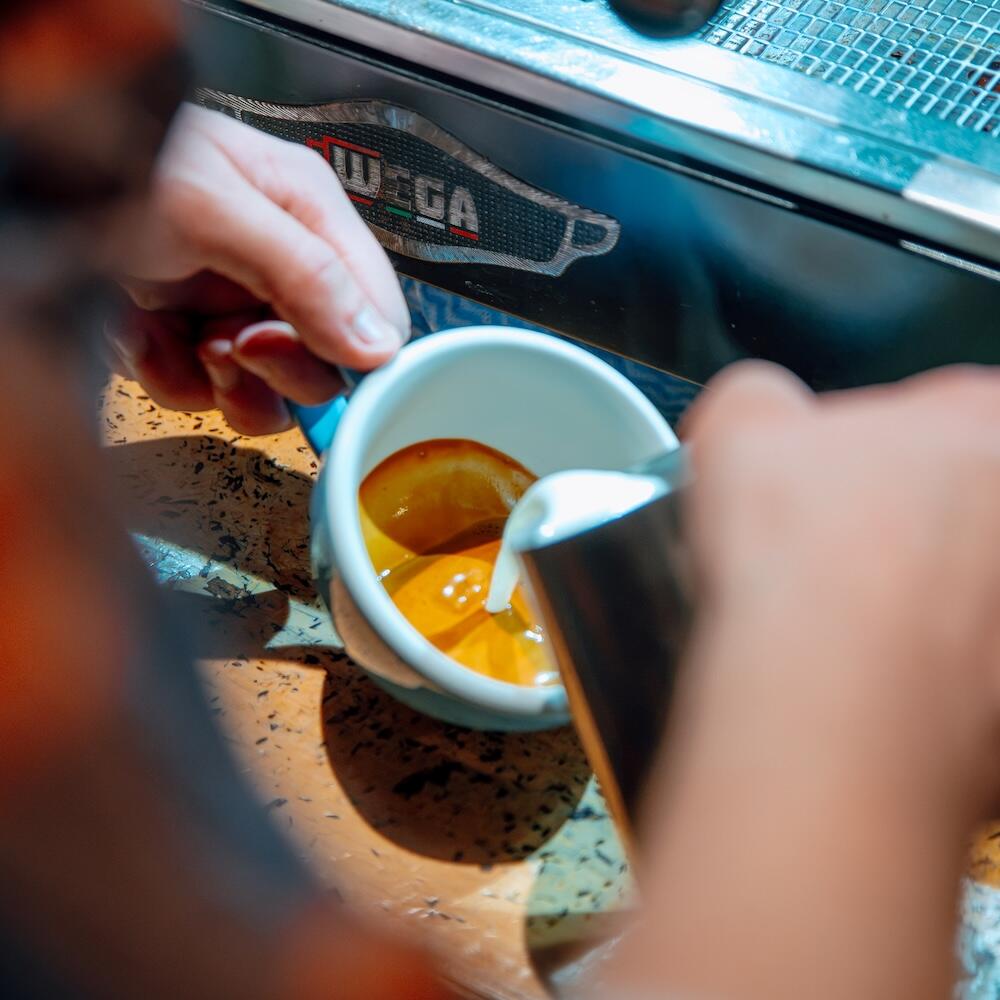 Barista pouring steamed milk into an espresso at Biddy Kate's, Blenheim